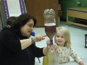 Submittted Preschool assistant Johnna Boksansky assists preschooler Piper Geiss with her science exper- iment at St. Helen Preschool.