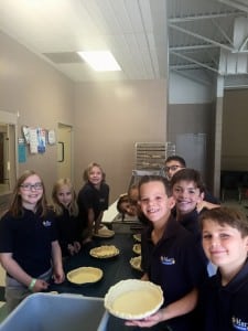 Submitted St. Mary fifth-graders work in an assembly line preparing the piecrusts for the apple filling.