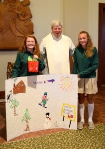 Submitted Father Jay appreciates the card presented by eighth-graders (l to r) Tess Ruggeri, of Russell Township, and Allison Barcikoski, of Huntsburg.