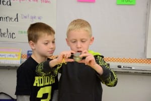 Submitted First-graders Kannon S. and Easton W. study an object to determine if it’s considered to be living or non-living. The experiment was part of a recent science lab held in class.