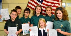 Submitted St. Helen fourth-graders (l to r) Ben LoGerfo, of Middlefield; Mario Romagni, of Burton; Daniel Novak, of Chardon; Seianna Coon, of Chardon; Julia Suvak, of Russell Township; and Meagan Passow, of Russell Township, display letters they are sending to Marine Corps recruit Colin Gaddis (not pictured). In front is Piper Geiss, cousin of Gaddis.