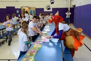 Submitted Burton Elementary School Principal Mandy Randles, dressed in a turkey costume in celebration of Thanksgiving, helps distribute books to third-graders. The books were a gift from East Geauga Kiwanis Club.